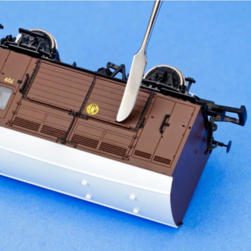 Model train car with a carving tool on a blue background
