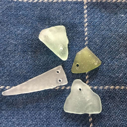 four pieces of drilled sea glass using the diamond core drills and diamond tipped drill bits